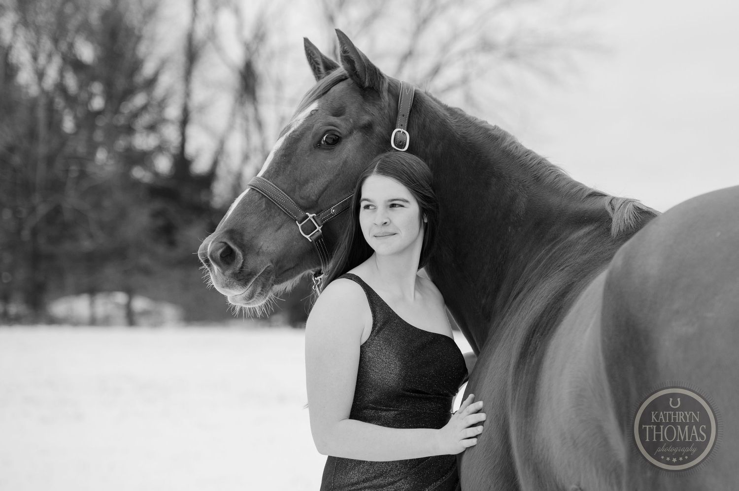 A black and white portrait of a person and horse against a snowy winter backdrop.