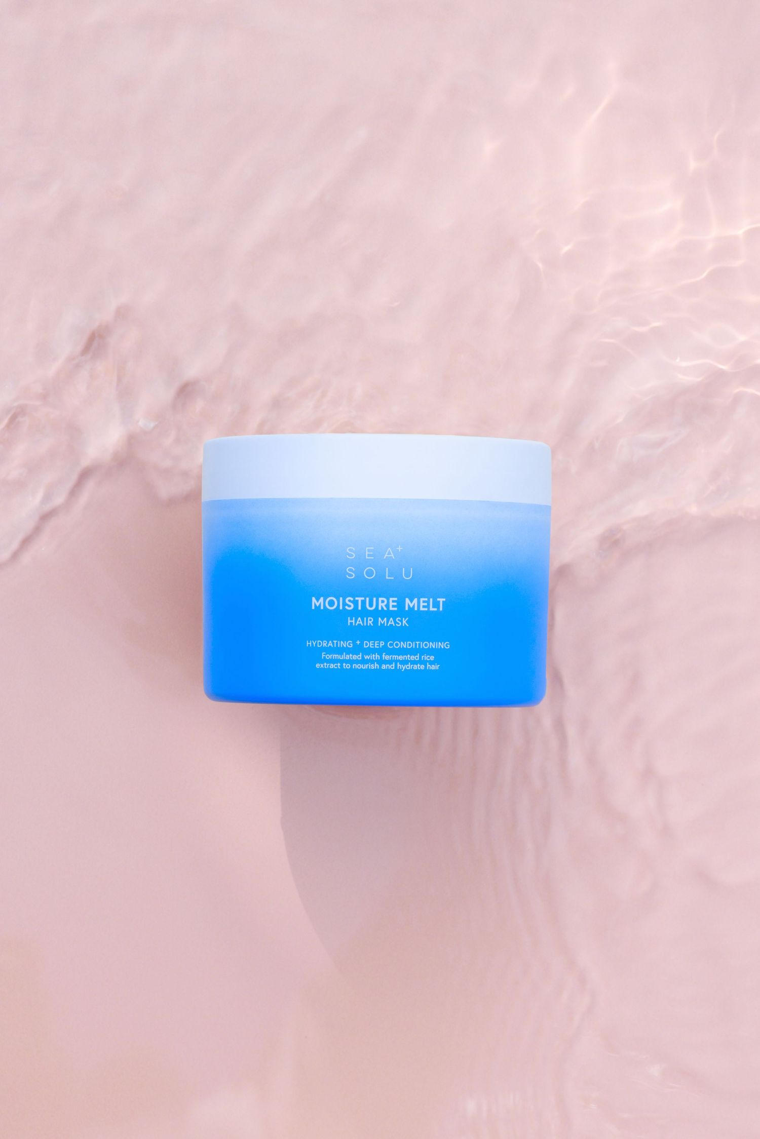 Blue hair mask jar on pale pink water ripple textures background displaying Moisture Melt product packaging.