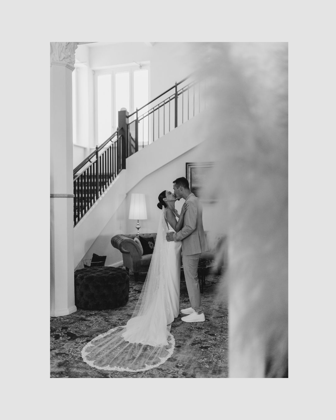 Black and white wedding photo with couple embracing on elegant staircase.