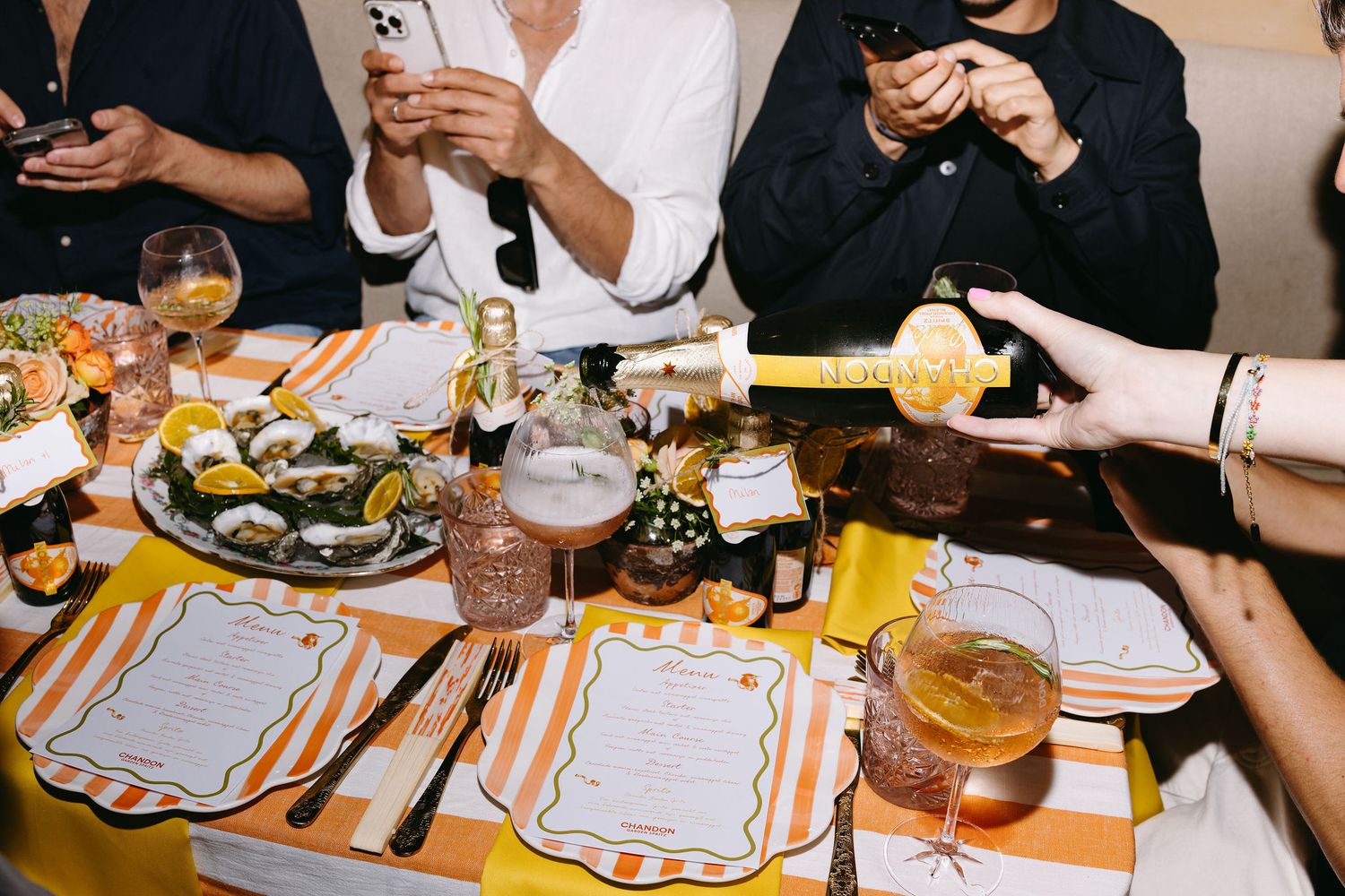 Dining table set with orange-trimmed menus and place settings for a celebratory meal.