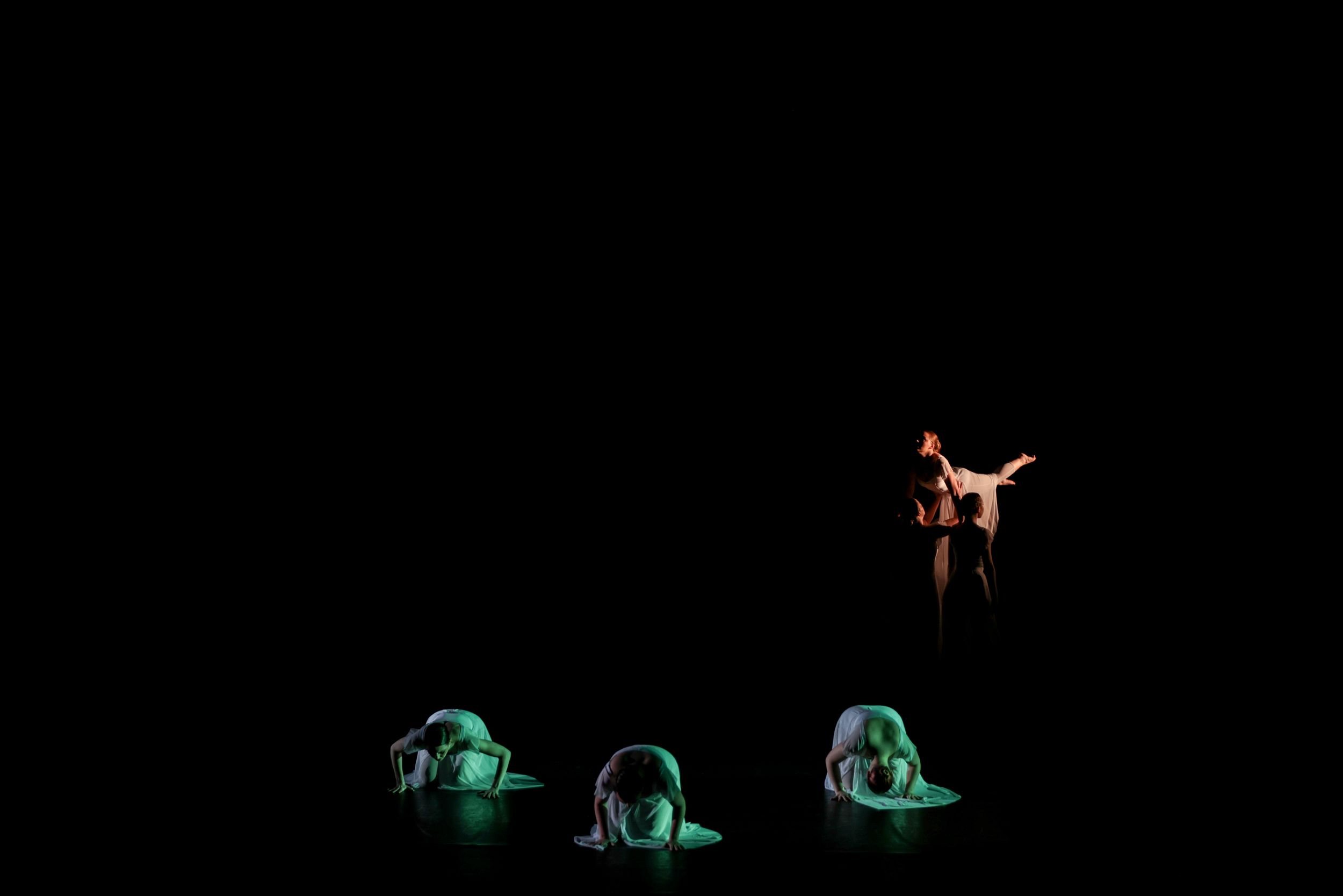 Modern dance performance with dancers in silhouette against black background creating striking visual formations. Theatre photography.