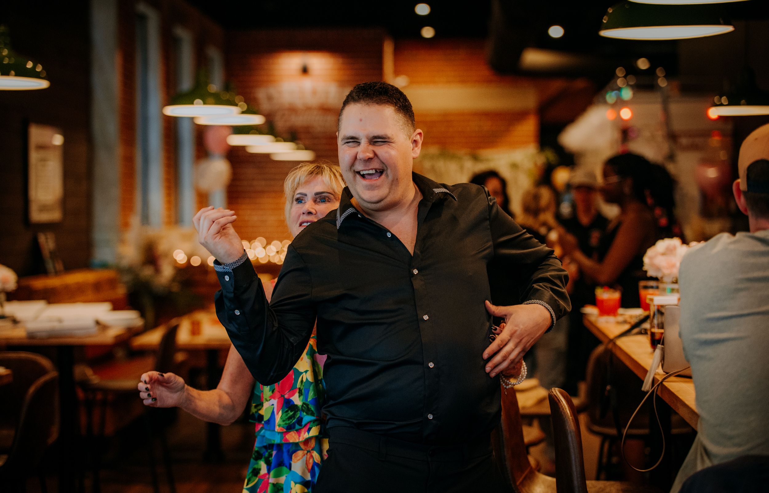 People dancing and celebrating at a lively indoor reception or party with warm lighting and festive atmosphere.