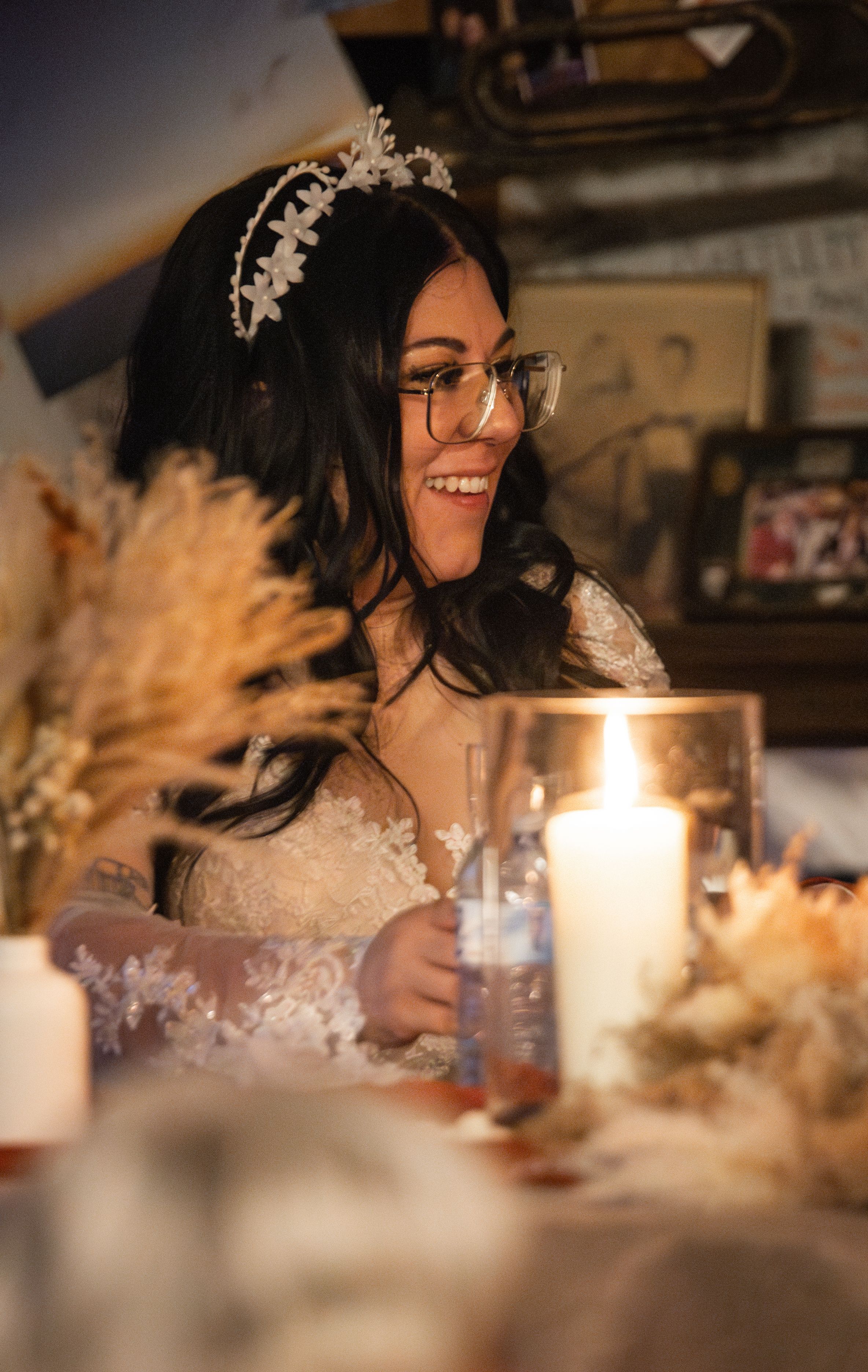 A candlelit wedding table decorated with pampas grass and featuring a bride wearing a crystal tiara.