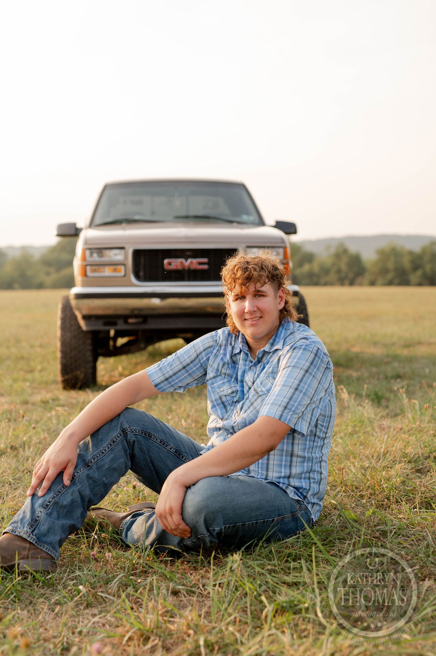 A relaxed outdoor portrait with a classic GMC truck in a sunlit field.