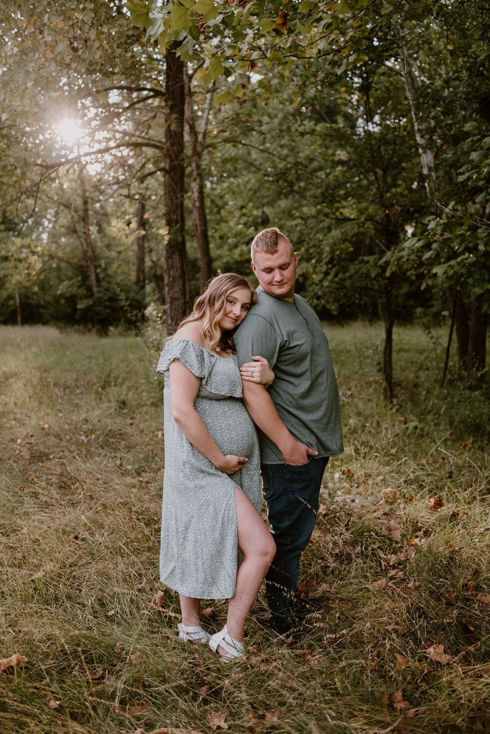 A couple poses together on a wooded trail during their maternity photography session.