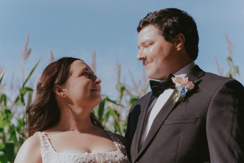 Newlywed couple shares a romantic moment together in front of a cornfield on their wedding day.