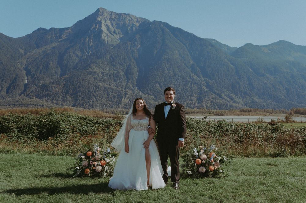 Outdoor mountain wedding ceremony setup with floral arrangements in a scenic mountain valley meadow.