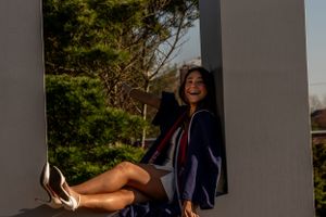 Girl smiling in a graduation gown, celebrating her achievement with joy and pride.