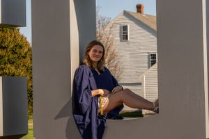 Girl smiling in a graduation gown, celebrating her achievement with joy and pride.