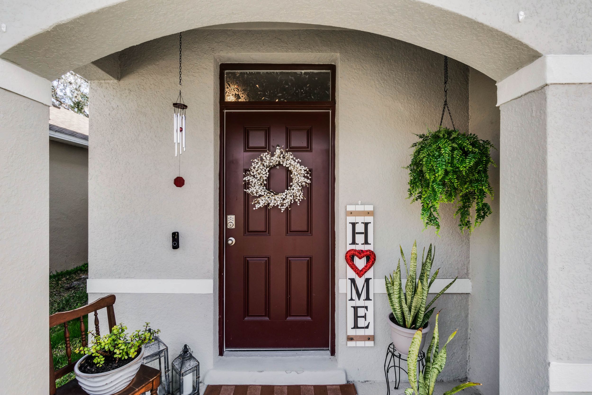 Modern home entrance with decorative door and hanging plants.