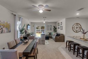 Modern open concept living room with white walls, ceiling fan, and comfortable seating arrangement.