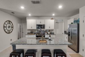 Bright kitchen with granite countertops, white cabinets, and stainless steel appliances.