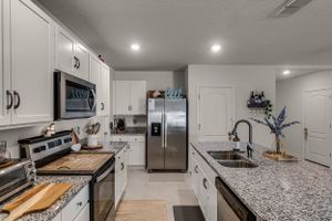 Contemporary kitchen featuring speckled granite countertops and white shaker cabinets with modern hardware.