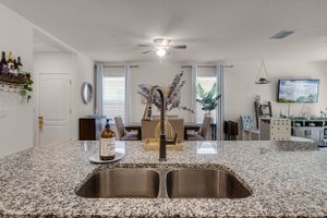 Granite kitchen countertop with undermount sink and modern faucet in bright white kitchen.