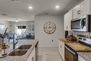 Open concept kitchen and living space with granite counters and modern lighting fixtures.