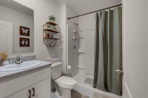 Sleek bathroom with white vanity, framed mirror, and olive green shower curtain.