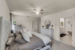 Spacious master bedroom with neutral decor, ceiling fan, and natural light.