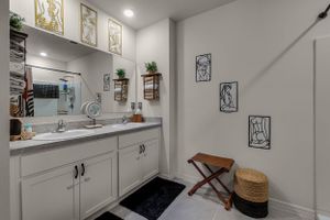 White bathroom with extended countertop, storage cabinets, and decorative wall accents.