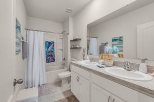 Clean white bathroom with double vanity, large mirror, and modern fixtures.
