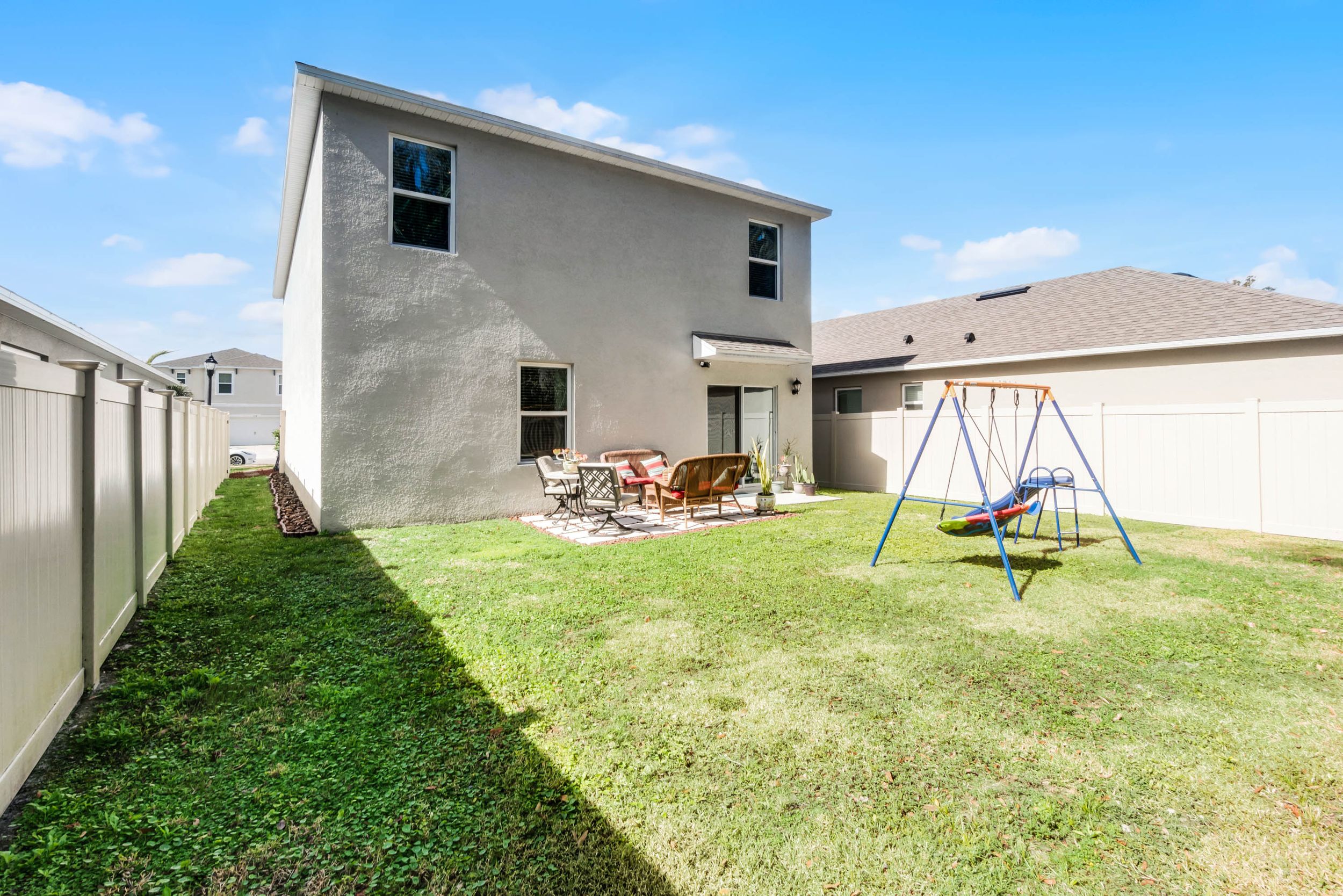 Spacious backyard with green lawn and children's playground equipment visible in the distance.