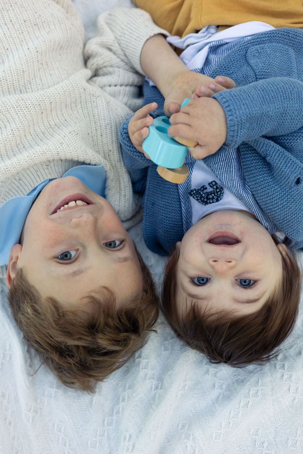 2 young boys look up at the camera upside down.