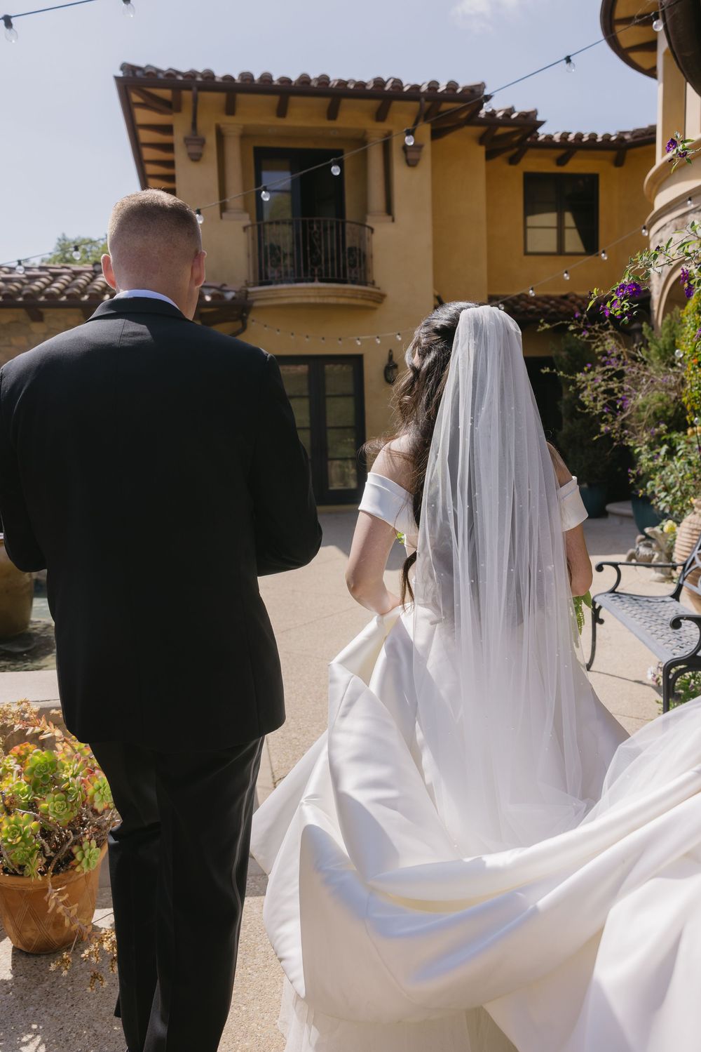 A series of wedding photographs showing the back view of a couple with flowing white bridal veil and dark suit outdoors.