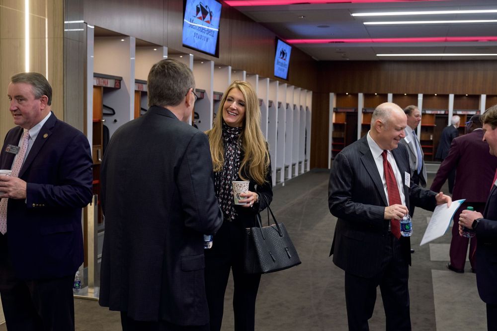 People gathering in a stadium corridor near lockers.
