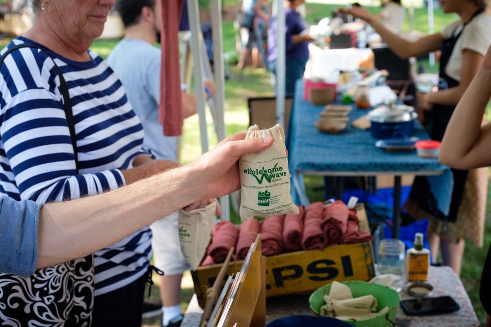 Customer examining products at an outdoor market stand with striped shirt.