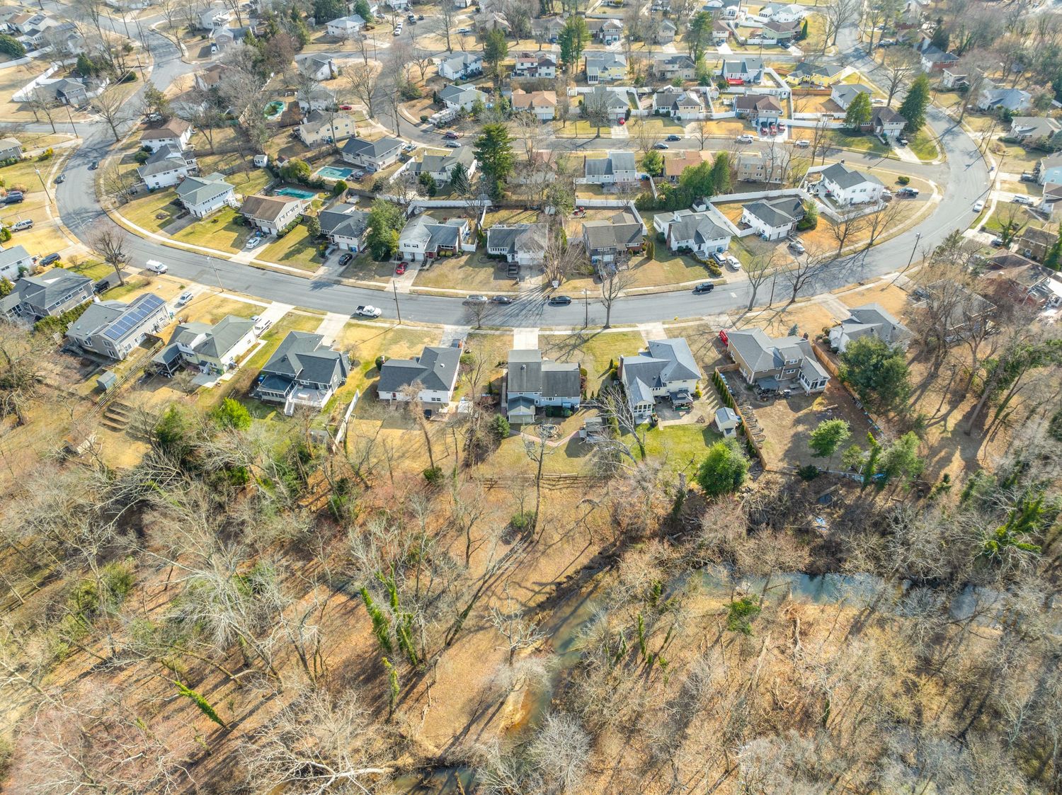 Aerial view of a curved suburban street with homes arranged in a semicircle pattern against brown winter terrain.