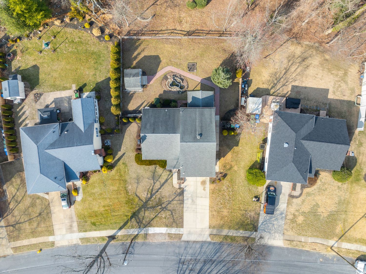 Aerial view of suburban homes with grey roofs along a curved street during winter.