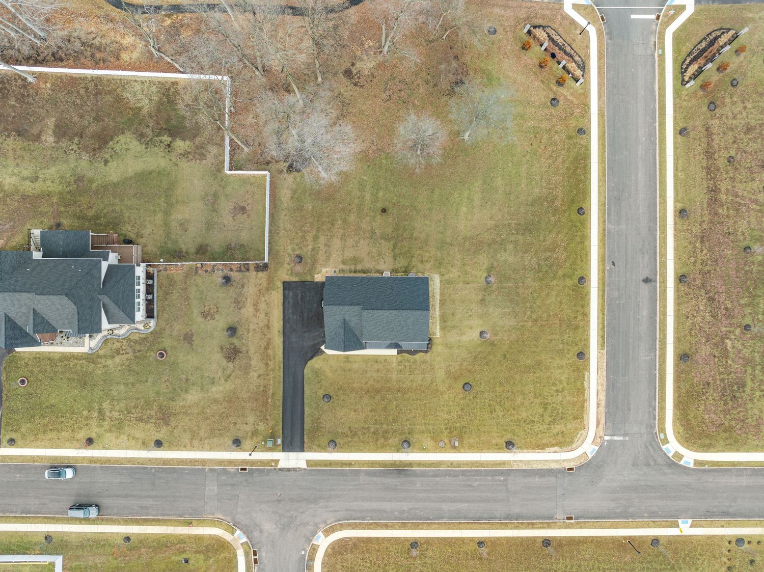 Aerial view of residential lots with two houses and paved streets in a developing suburban neighborhood.