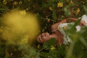 Bride resting peacefully among lush garden foliage with golden sunlight filtering through leaves.