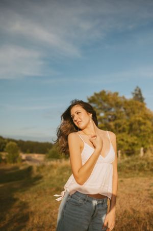 Golden hour countryside portrait with windswept hair against rolling hills.