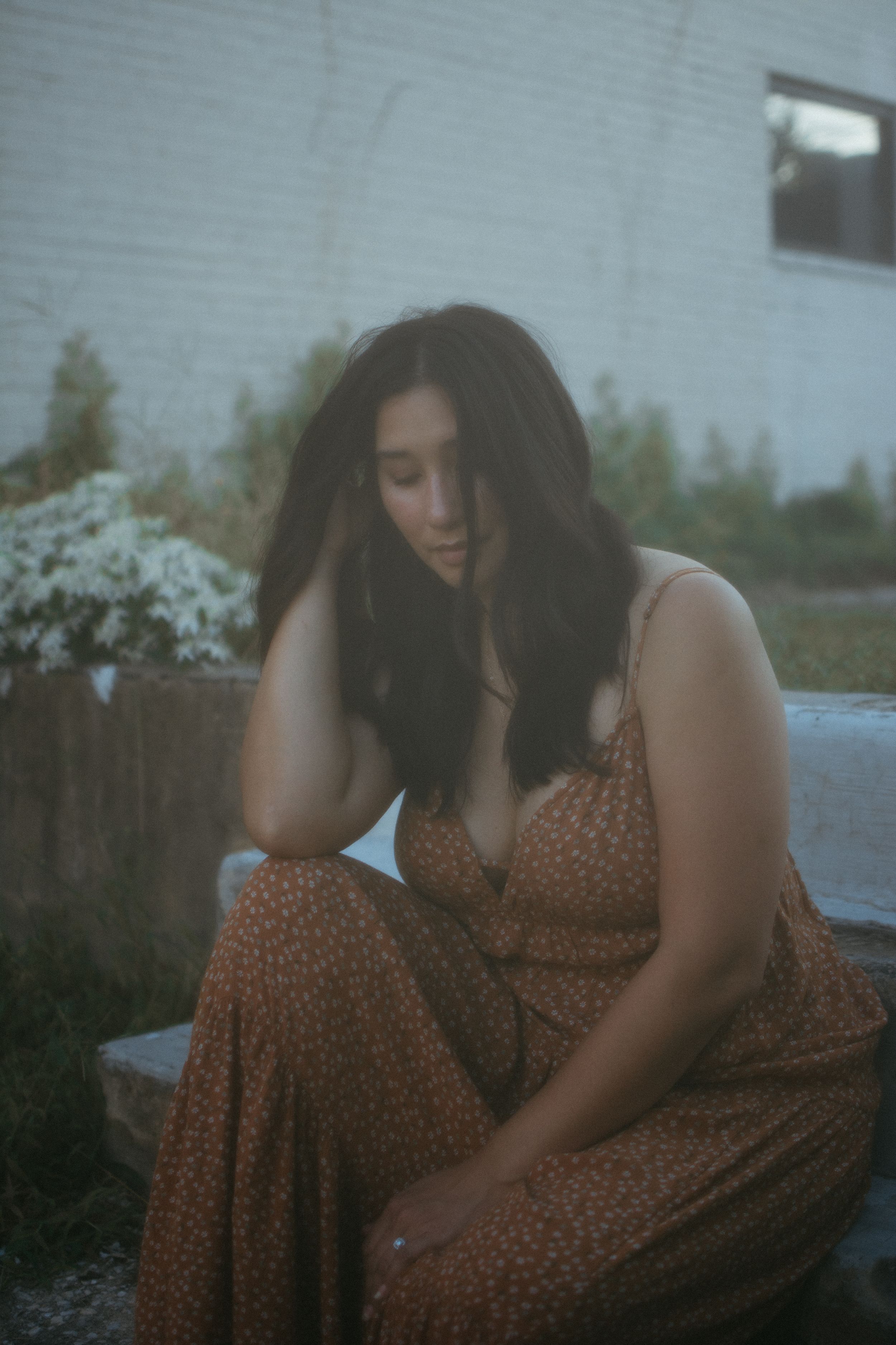 woman sitting down on stairs outside playing with her hair and looking down
