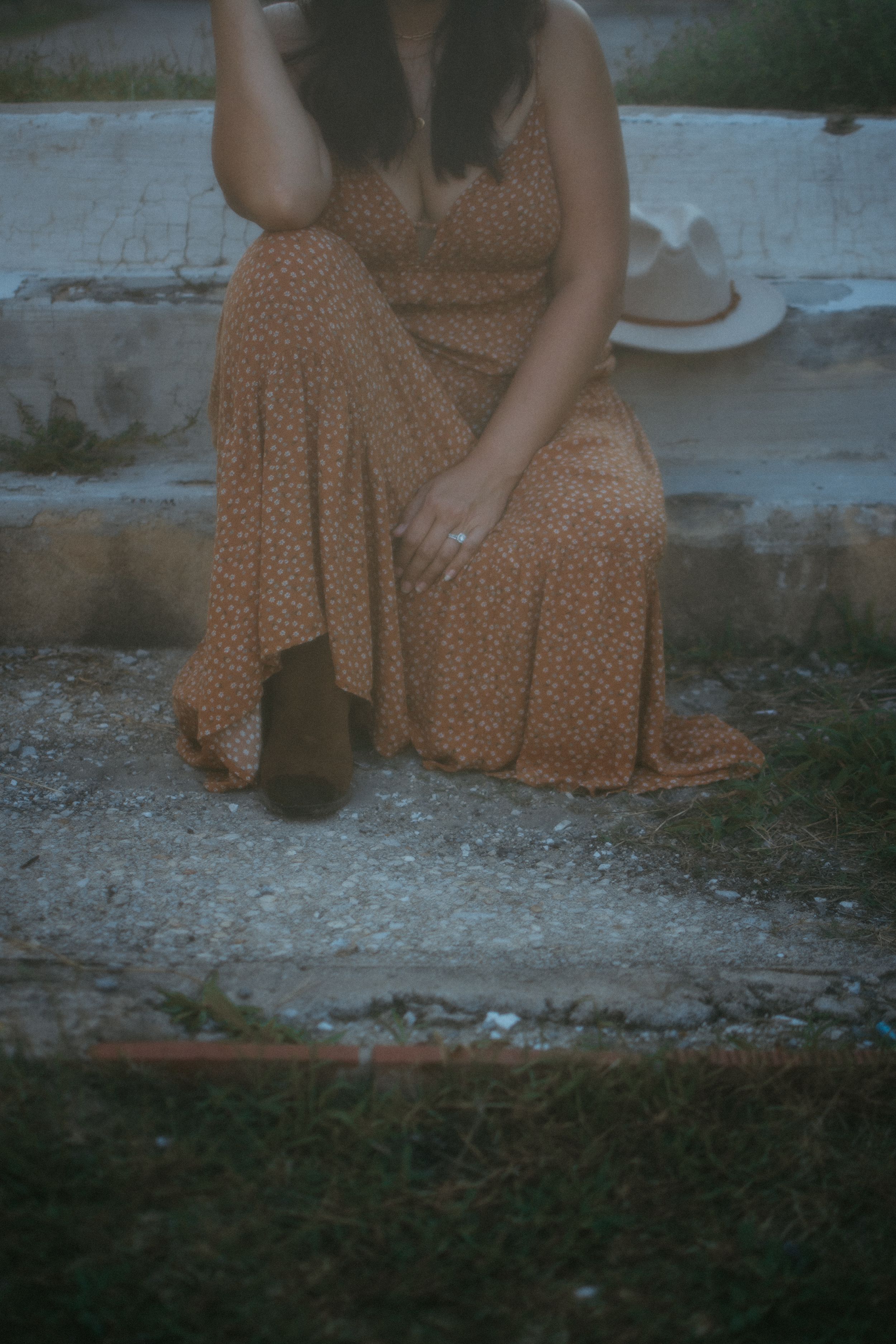 woman in an orange dress sitting relaxed on a curb