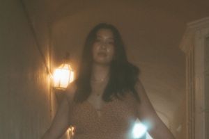 woman walking down a dimly lit hallways looking into the camera