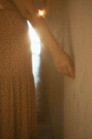 close up of a woman's hand grazing along a stone wall with light shining in the background