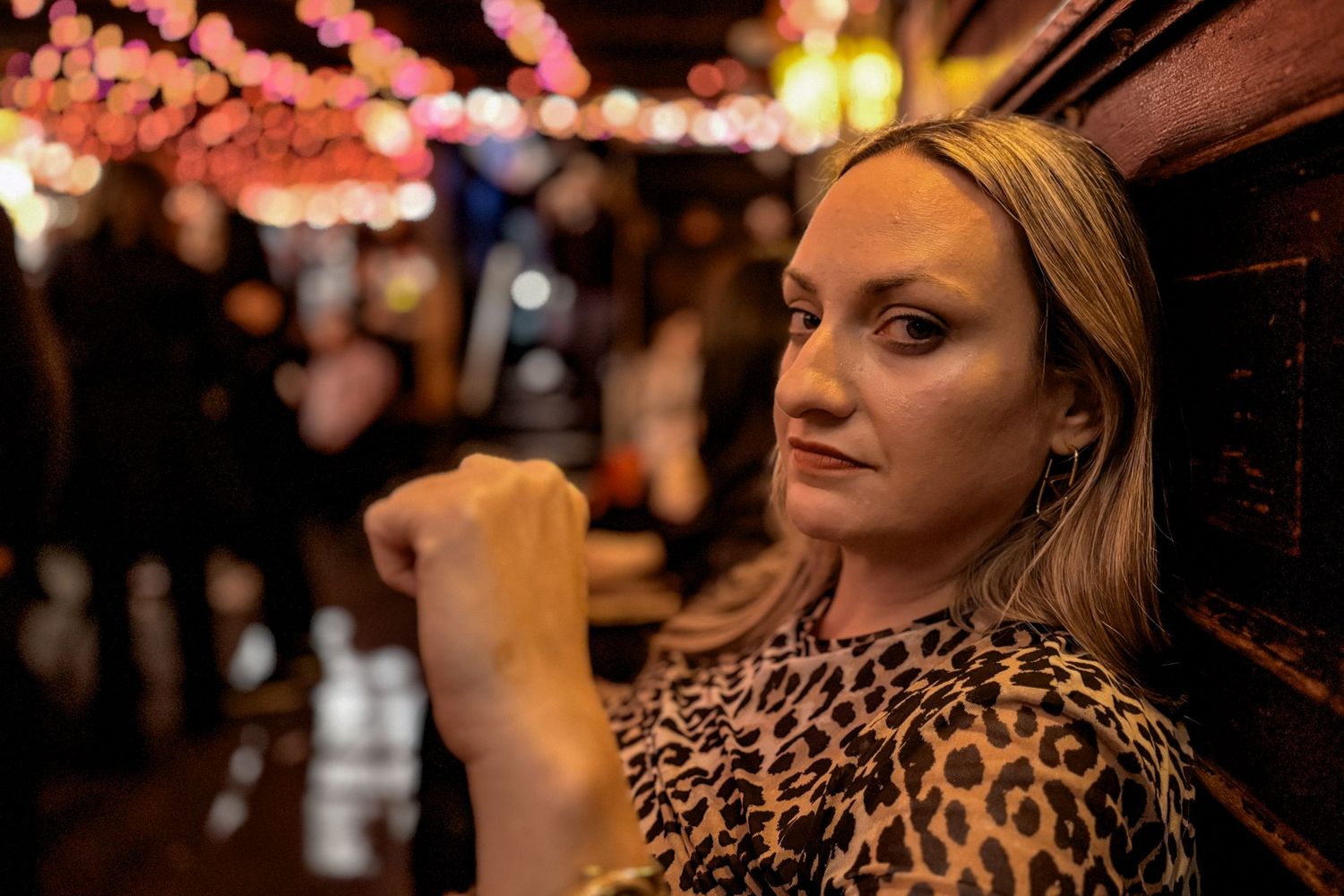 A portrait in a dimly lit bar with festive string lights creating a warm ambiance.
