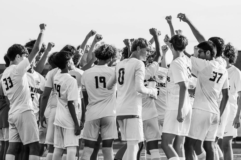 Soccer team celebrates together with raised fists in a black and white victory moment.