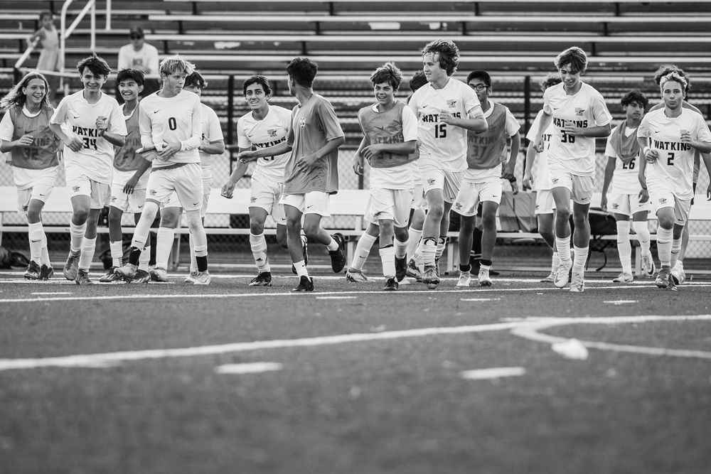 Soccer team members walk together across the field in black and white photography.