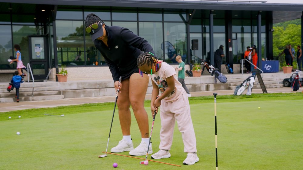 Golfers practicing their putting skills on a lush green practice putting area at a golf facility.