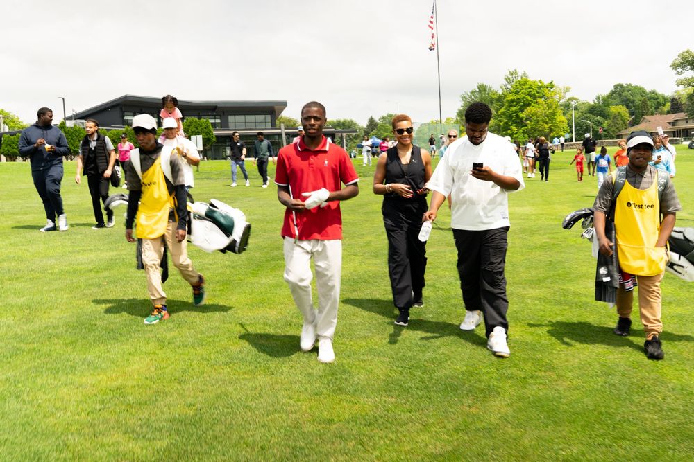 A group of people participate in an outdoor line dancing event on a green grass field.