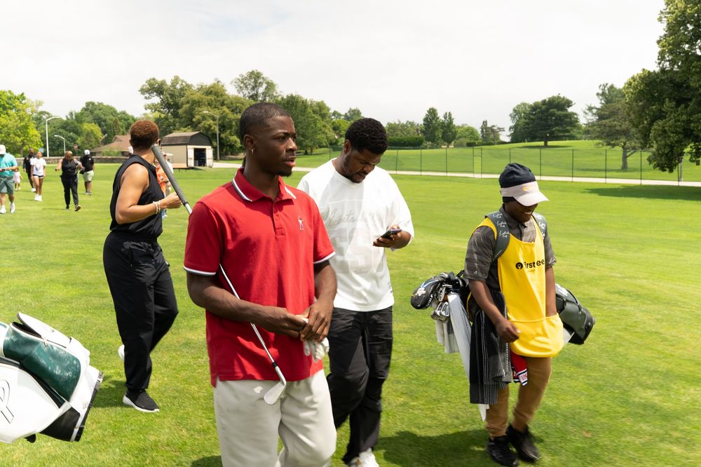 Golfers practicing their swings and receiving instruction on a lush green driving range.