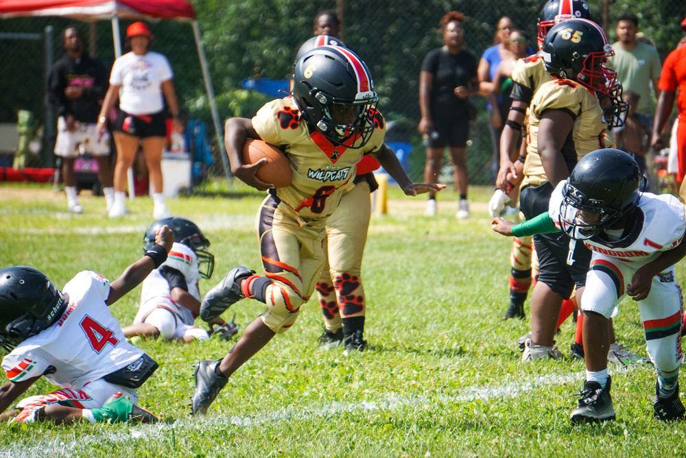 Youth football players stretch and warm up on a grassy field during practice or training session.