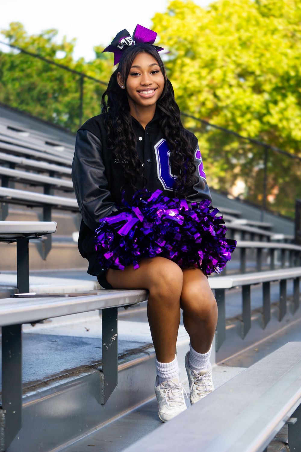 Cheerleader in black and purple uniform poses on stadium bleachers for a series of dynamic action shots.