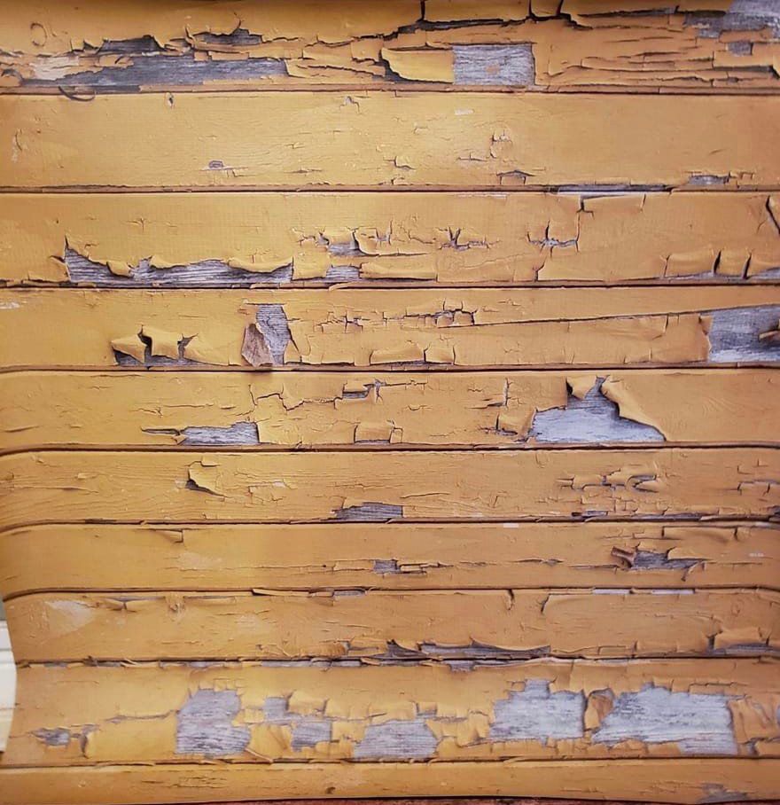 Distressed yellow wooden planks with peeling paint texture.