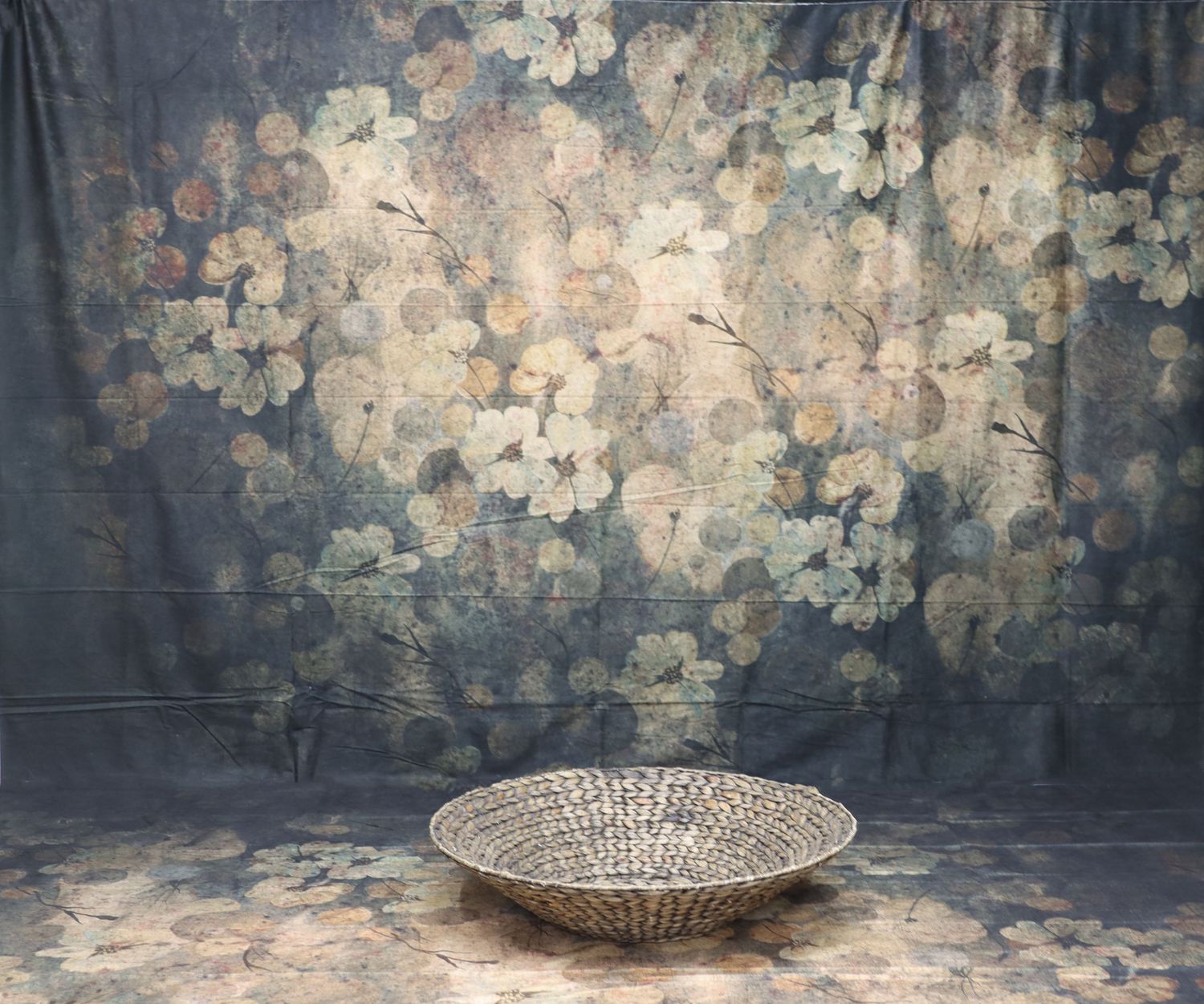 Vintage style backdrop with floral pattern and woven basket against dark background.