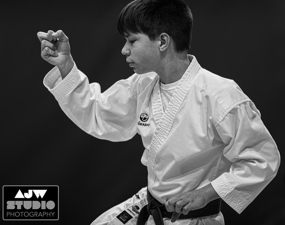 A martial arts student in white uniform demonstrates a focused stance during practice.