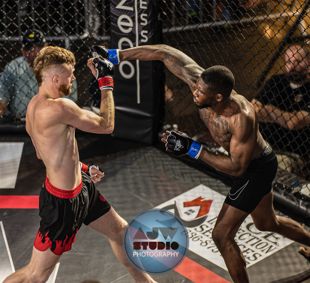 Two MMA fighters exchange strikes during an intense cage match with one throwing a powerful kick.