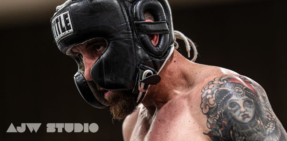 Combat sports athlete wearing protective headgear and displaying visible tattoos during training.